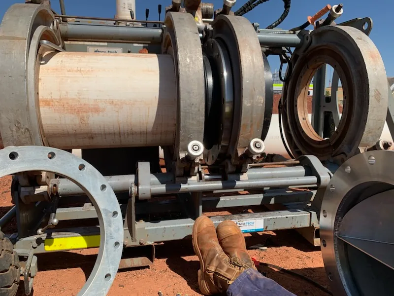 HDPE pipe fusion machine clamped onto pipe on a project site